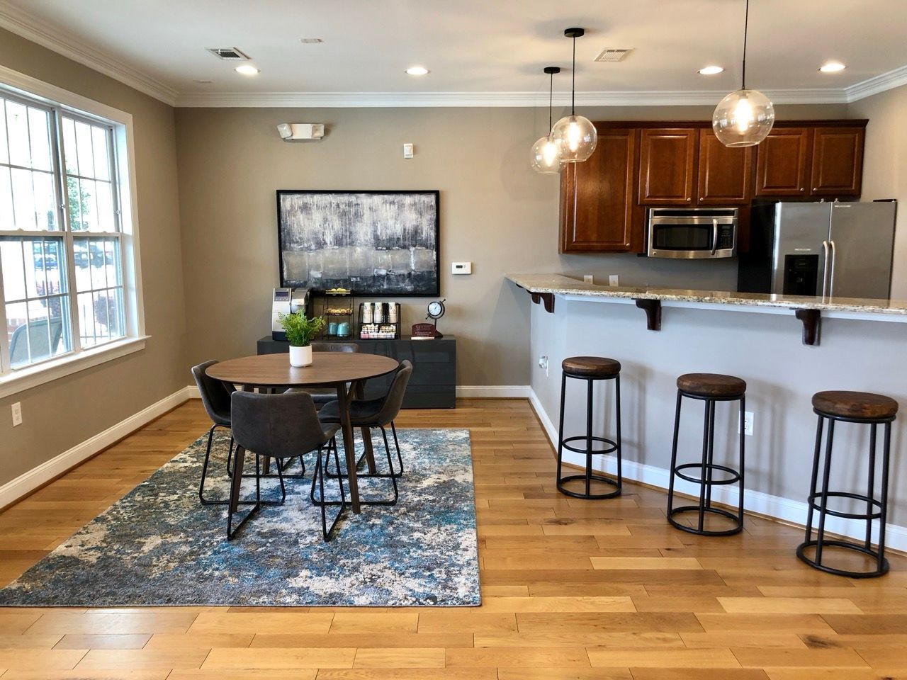 Bright open-concept kitchen and dining area in a modern apartment with a round table and bar stools.