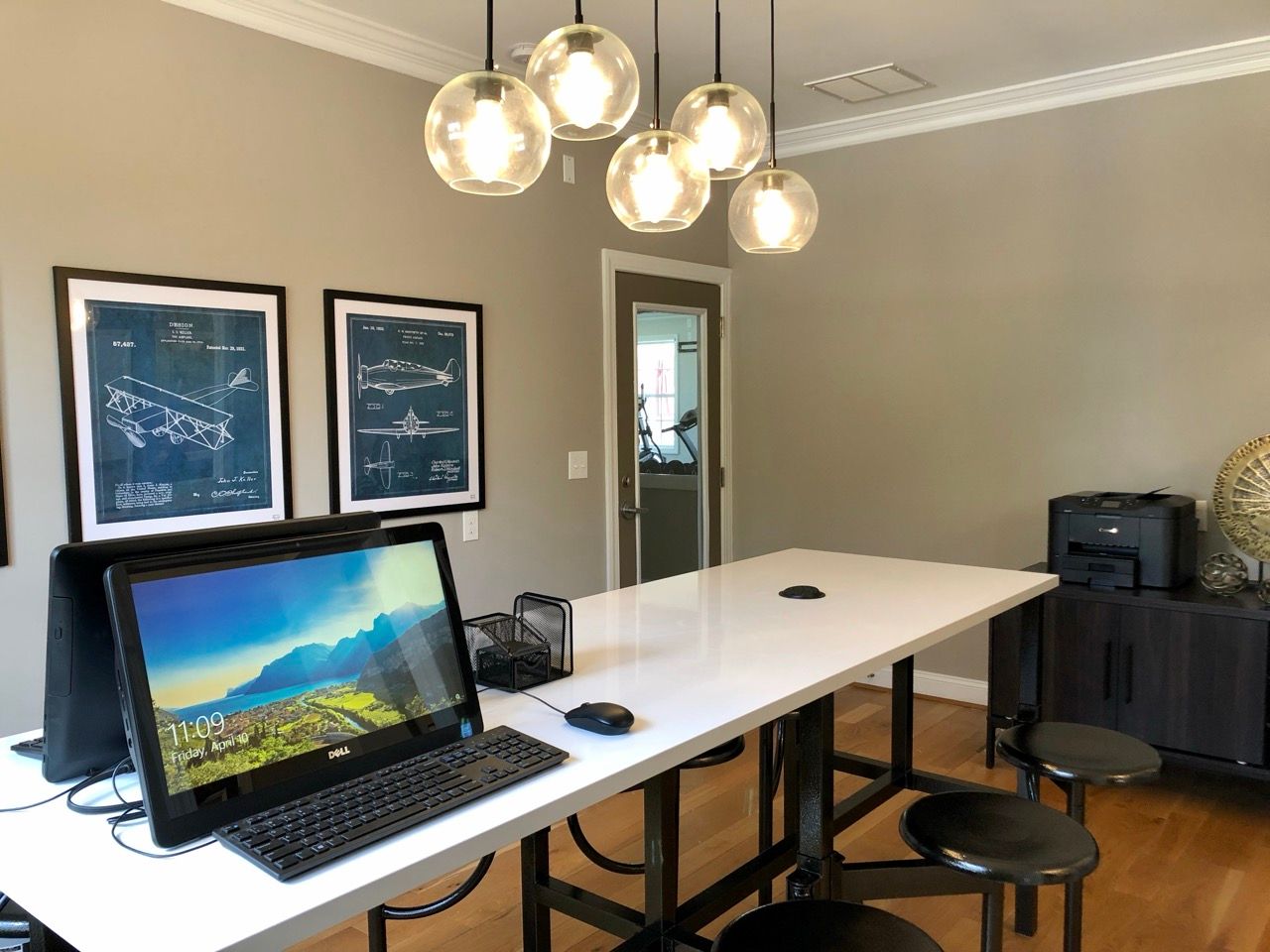 Modern apartment office with white desk, computer, and stools.