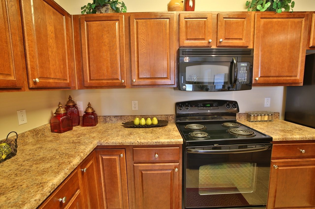 Kitchen interior with brown wooden cabinets, granite countertops, and a black microwave above the stove.