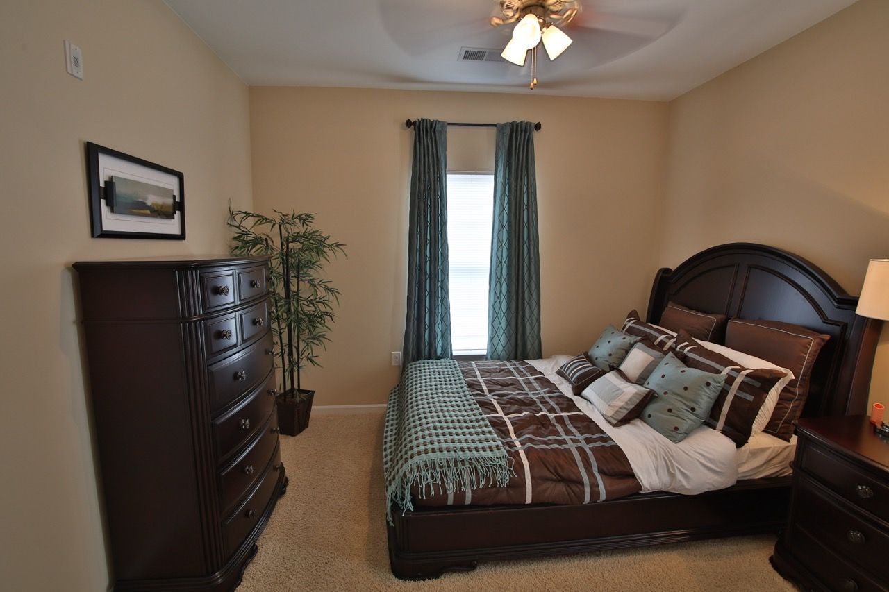 Bedroom with dark wood bed frame, tall dresser, and teal curtains.