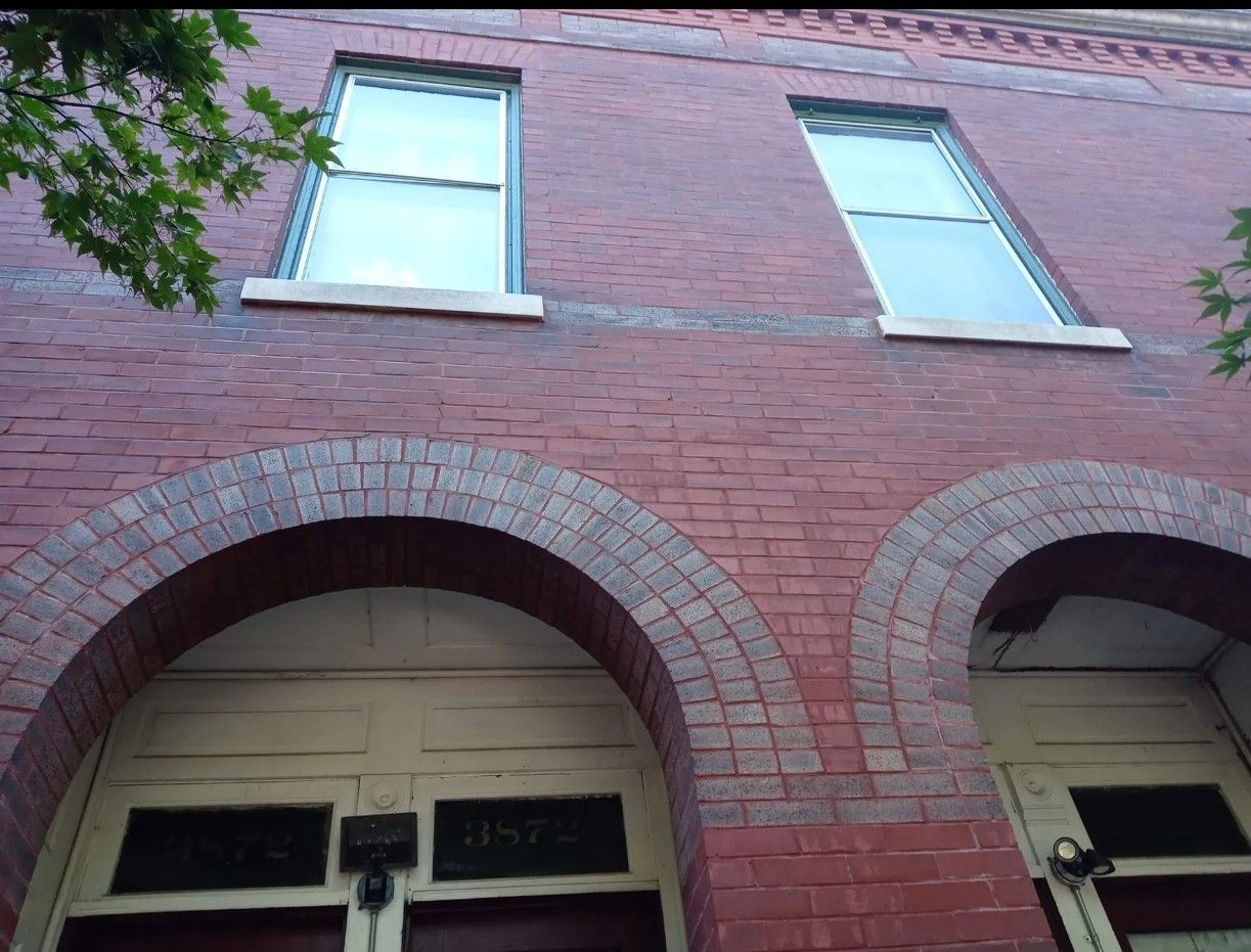 A kitchen with white cabinets , stainless steel appliances , and a large island with stools.