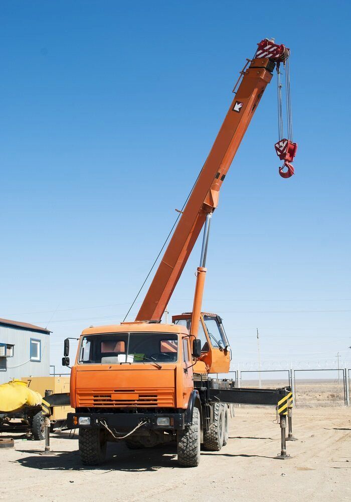 An Orange Truck With a Crane Attached to It — Smithys Crane Hire in Tully, QLD