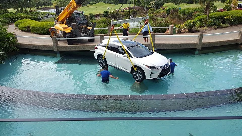White Car Is Being Lifted Out Of A Pool By A Crane — Smithys Crane Hire in Trinity Beach, QLD