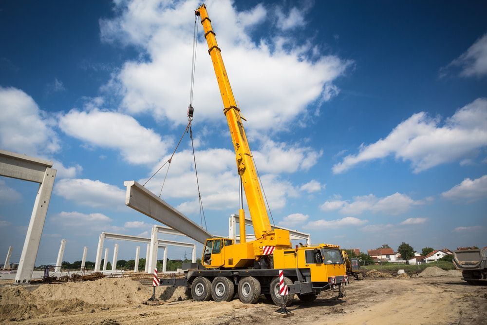 Yellow Crane Is Lifting A Concrete Beam on A Construction Site — Smithys Crane Hire in Trinity Beach, QLD