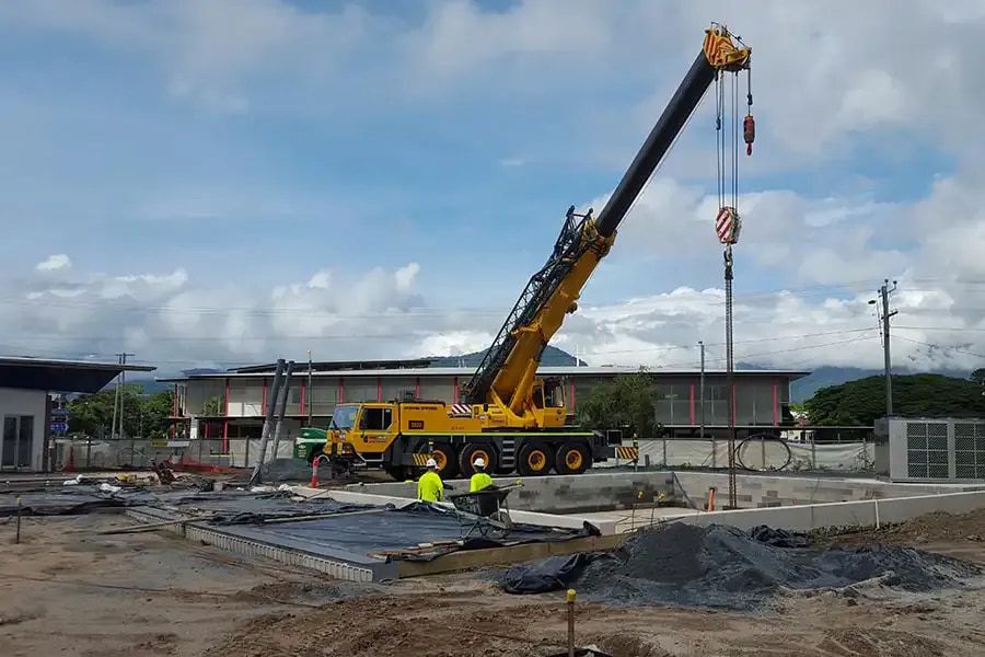 A Large Yellow Crane is Sitting on Top of a Construction Site — Smithys Crane Hire in Tully, QLD