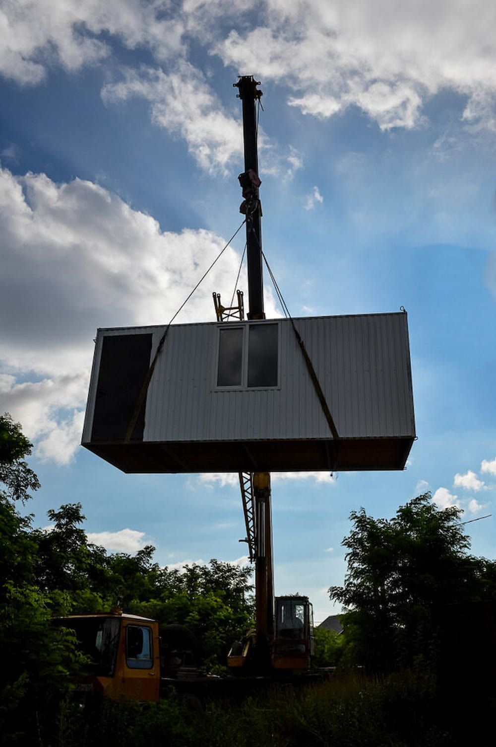 A Crane is Lifting a Container Into the Air — Smithys Crane Hire in Smithfield, QLD