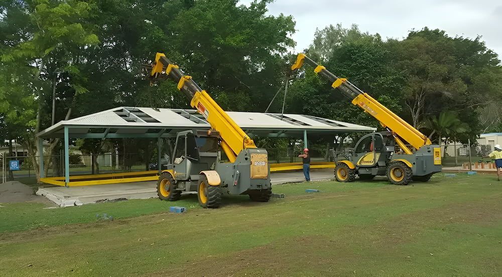 Two Yellow Tractors Are Parked in a Grassy Field — Smithys Crane Hire in Smithfield, QLD