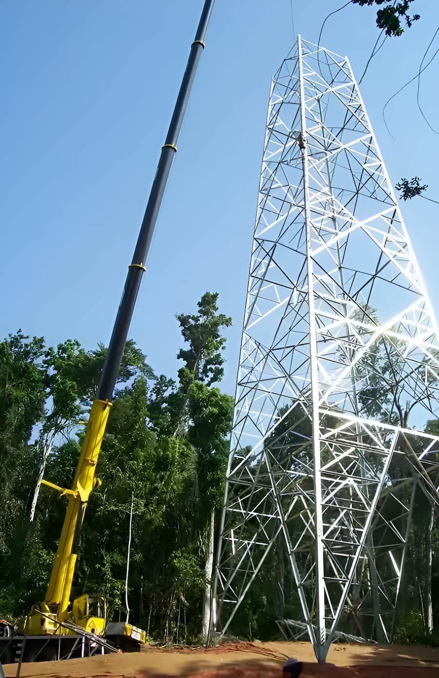 A Man is Standing Next to a Crane Lifting a Stack of Chairs — Smithys Crane Hire in Redlynch, QLD