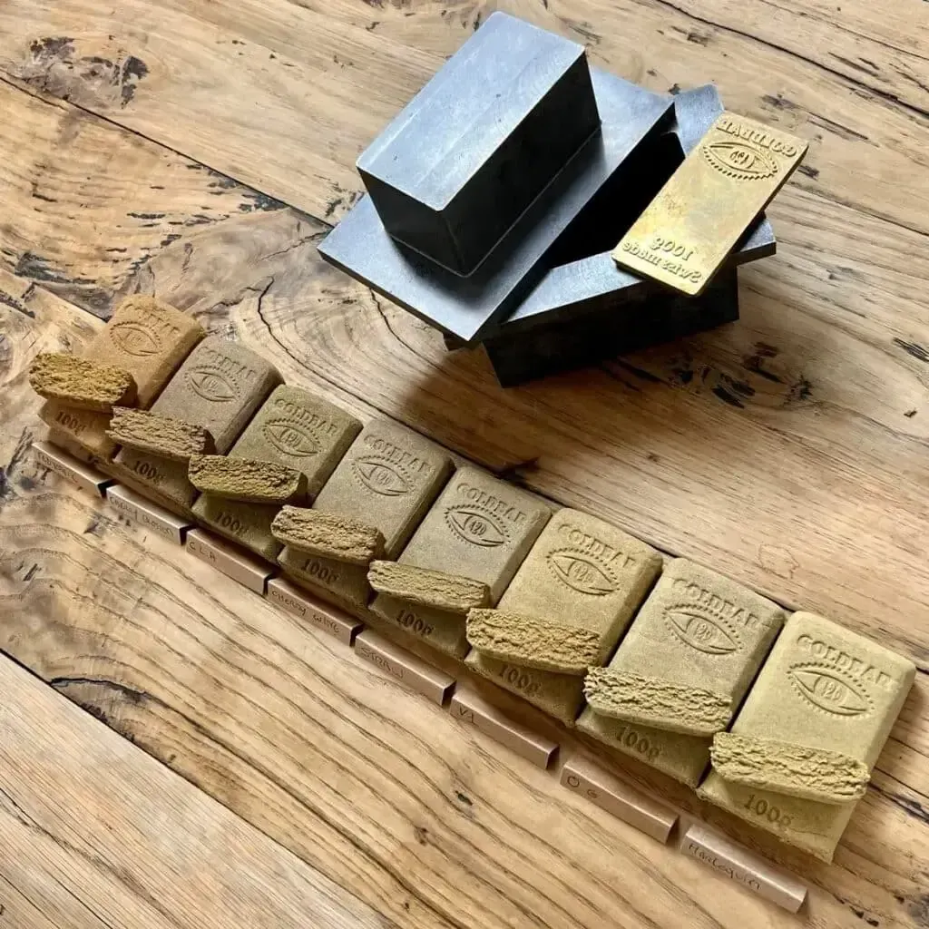 Une rangée de lingots d'or posés sur une table en bois.