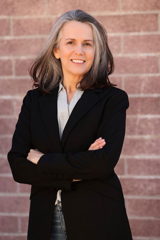 Real Estate Agent, Tanja Blackley stands in front of a brick wall, arms folded, smiling.