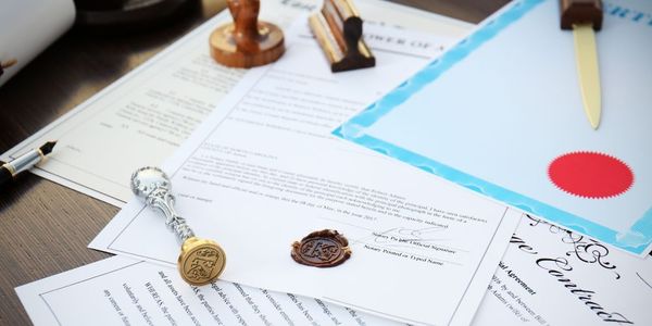 A table topped with papers , stamps , and a pen.