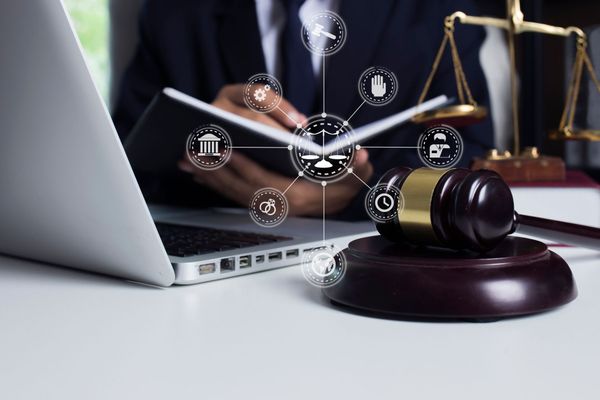 A judge is sitting at a desk with a laptop and a gavel.