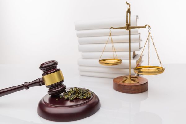 A judge 's gavel and scales of justice are on a table in front of a stack of books.