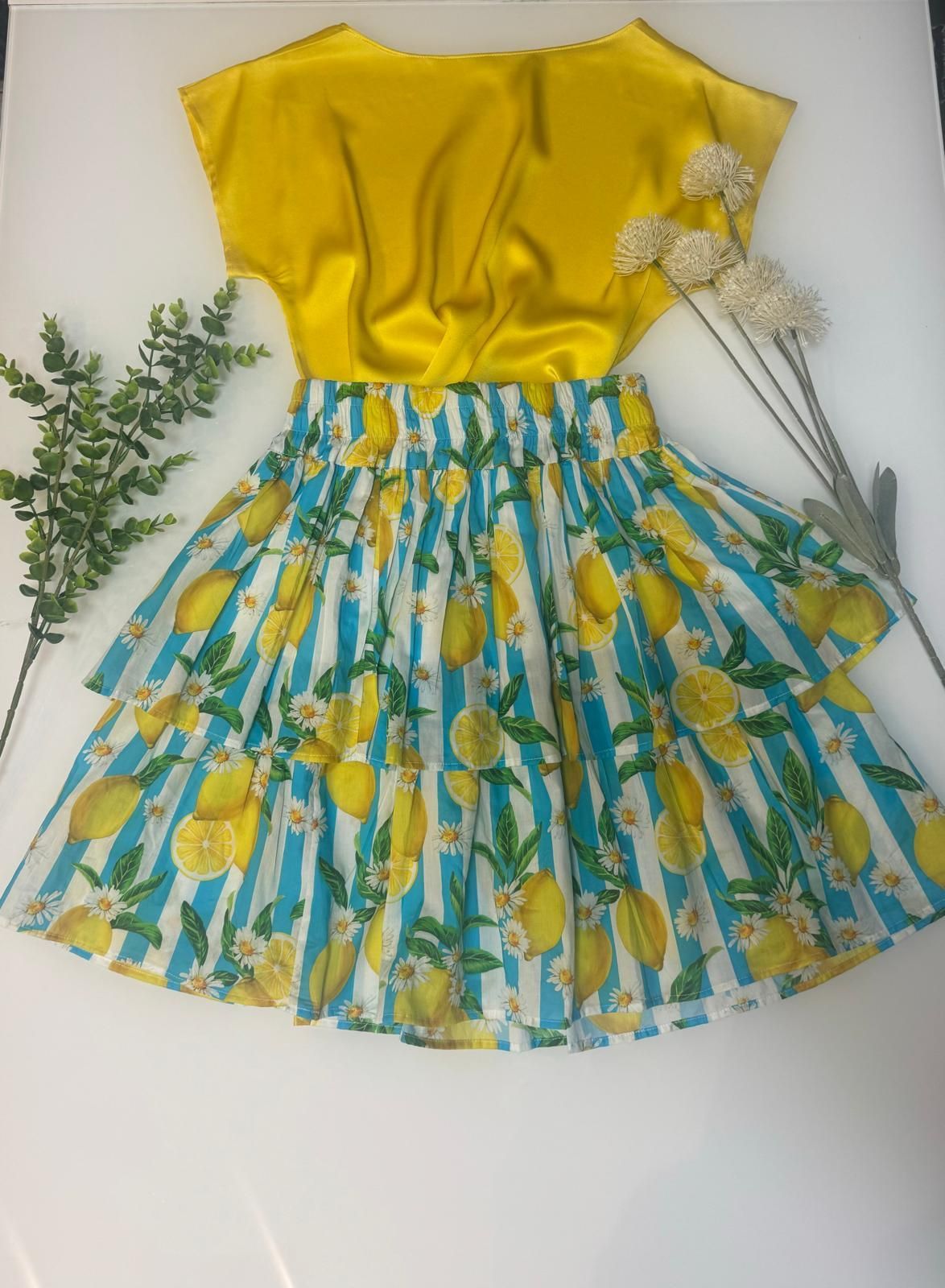 Un top giallo e una gonna blu e bianca con dei limoni sopra