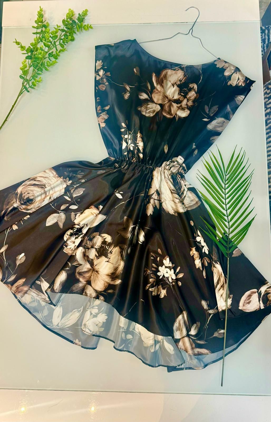 Un vestito nero con fiori sopra è appeso a una gruccia