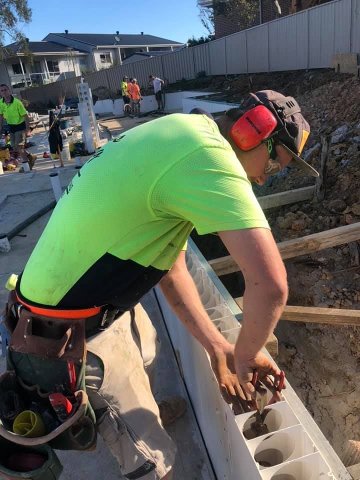 A man in a neon green shirt is working on a wall.