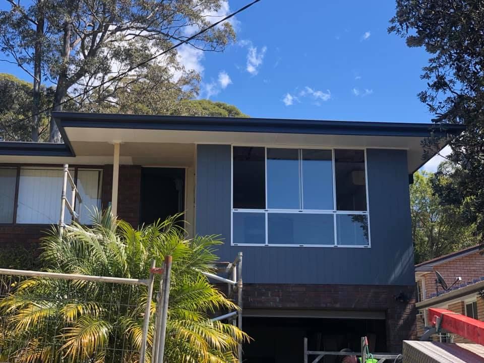 A blue house with a garage underneath it is being painted.