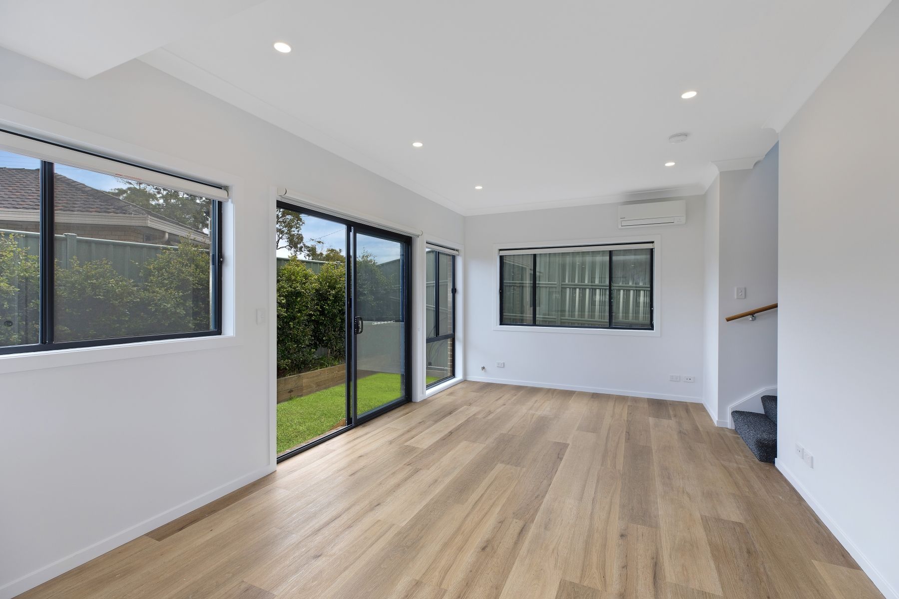 Two men are working on a brick wall in front of a house.