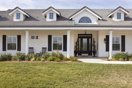 A large white house with black shutters and a large lawn in front of it.