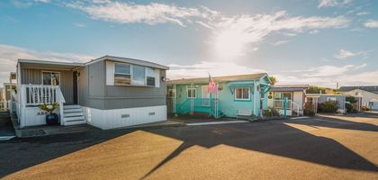 Mobile homes in Hemet CA. One is gray, the other turquoise, with a flag.