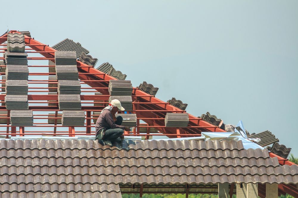 A man is sitting on top of a tiled roof.