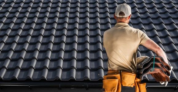 A man is standing on top of a tiled roof.