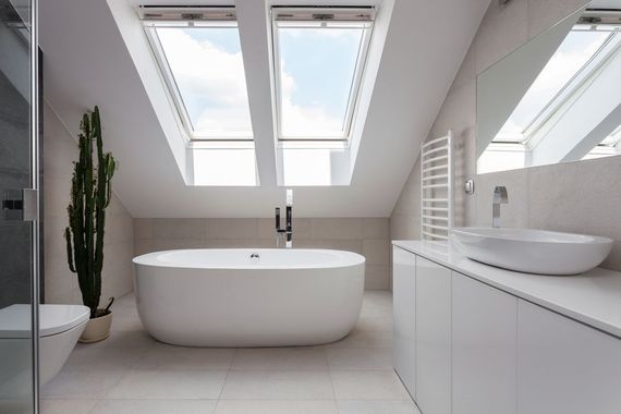 A bathroom with a bathtub , sink , toilet and skylights.