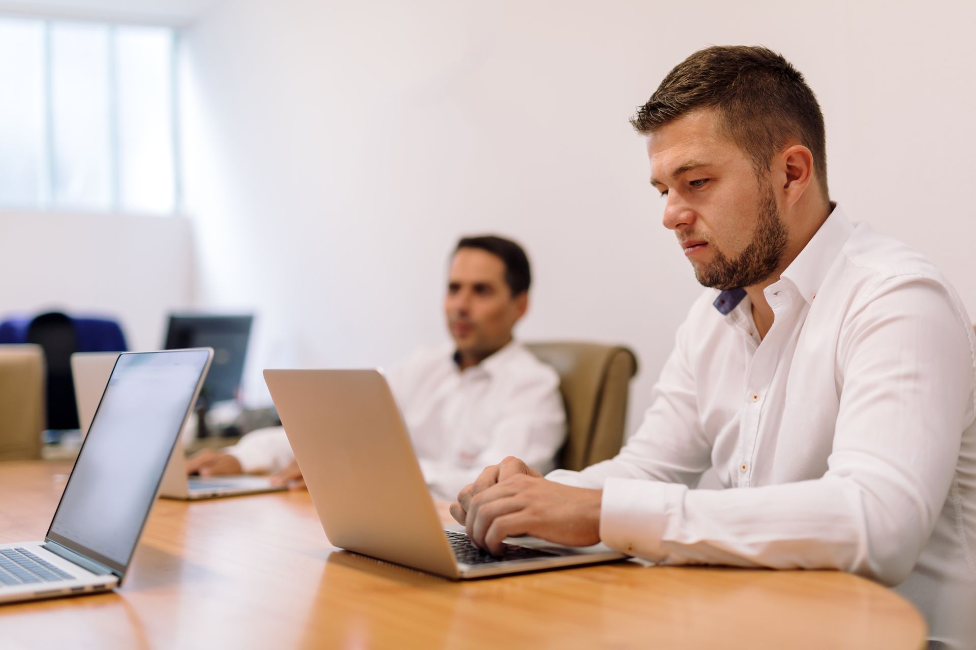 A man is sitting at a table using a laptop computer.