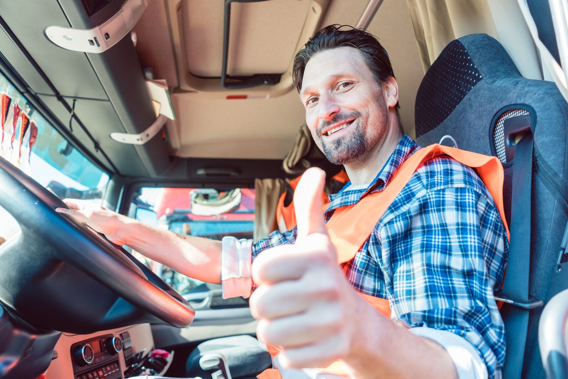 A man is sitting in the driver 's seat of a truck and giving a thumbs up.