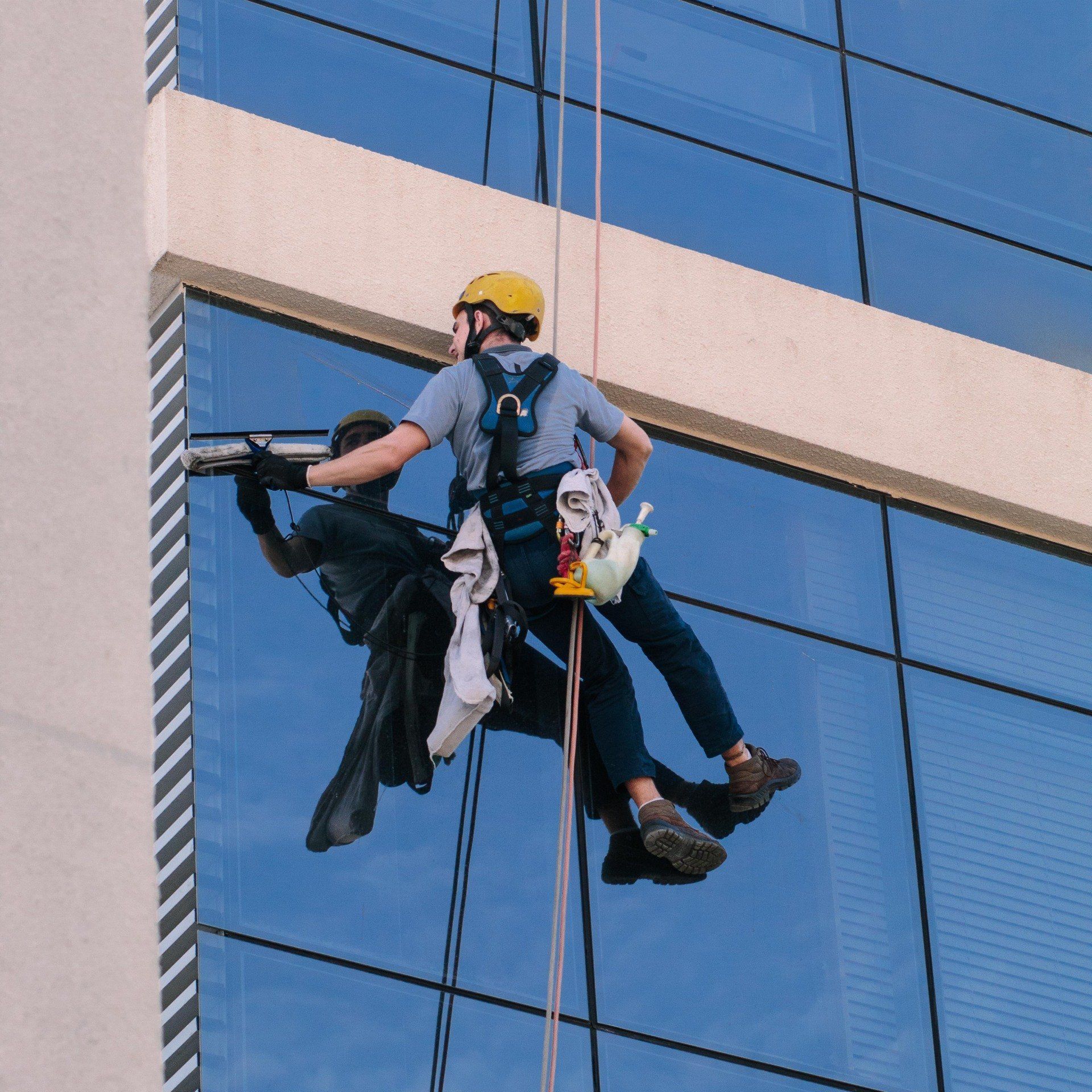 Man hanging  from wire cleaning windows