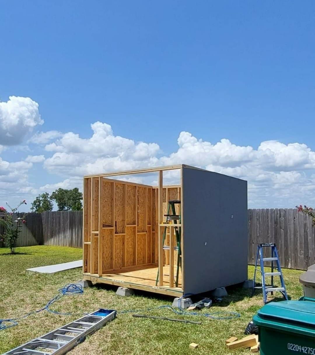 A small wooden shed is being built in a backyard.