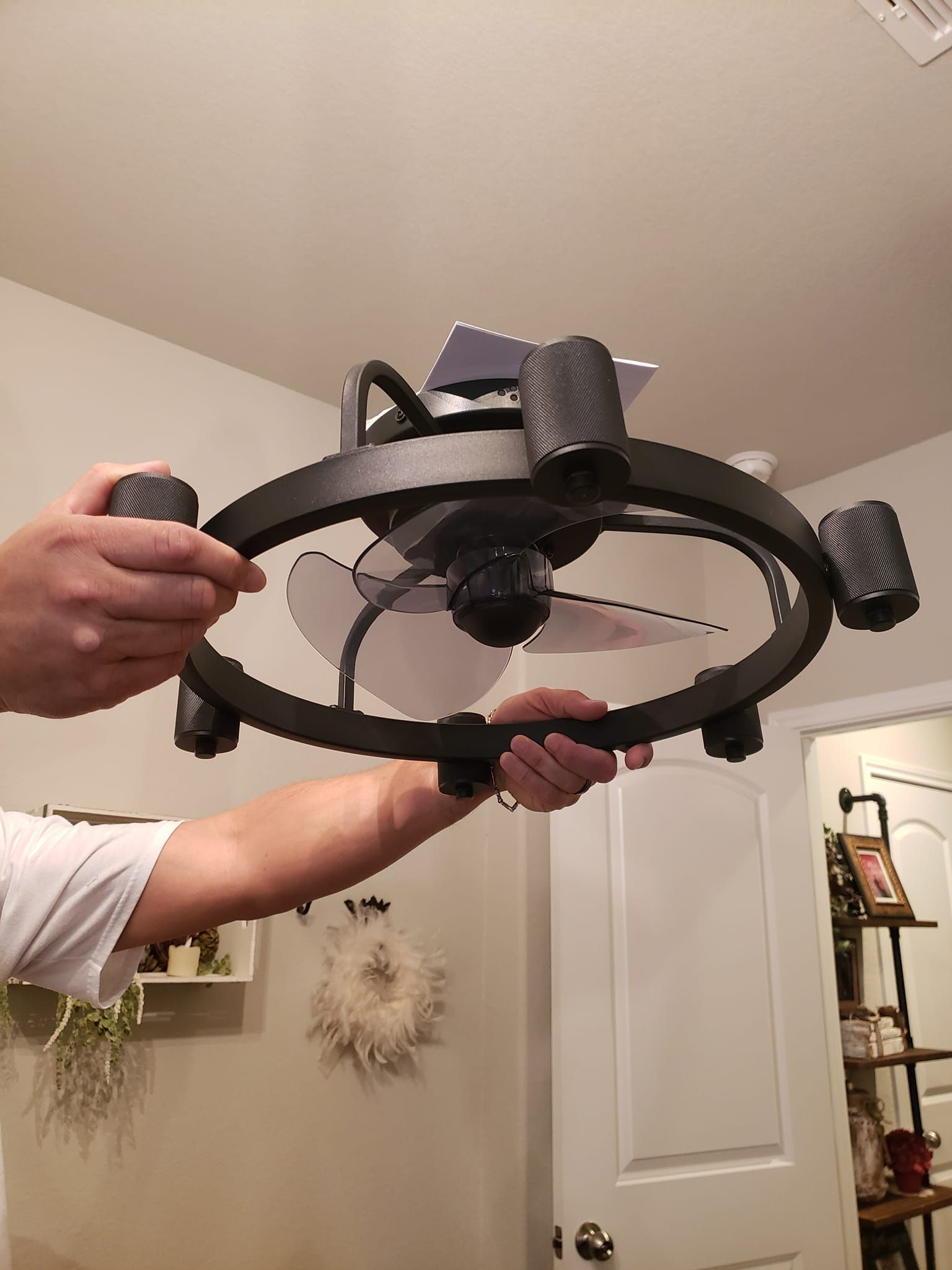 A person is holding a ceiling fan in their hands in a room.