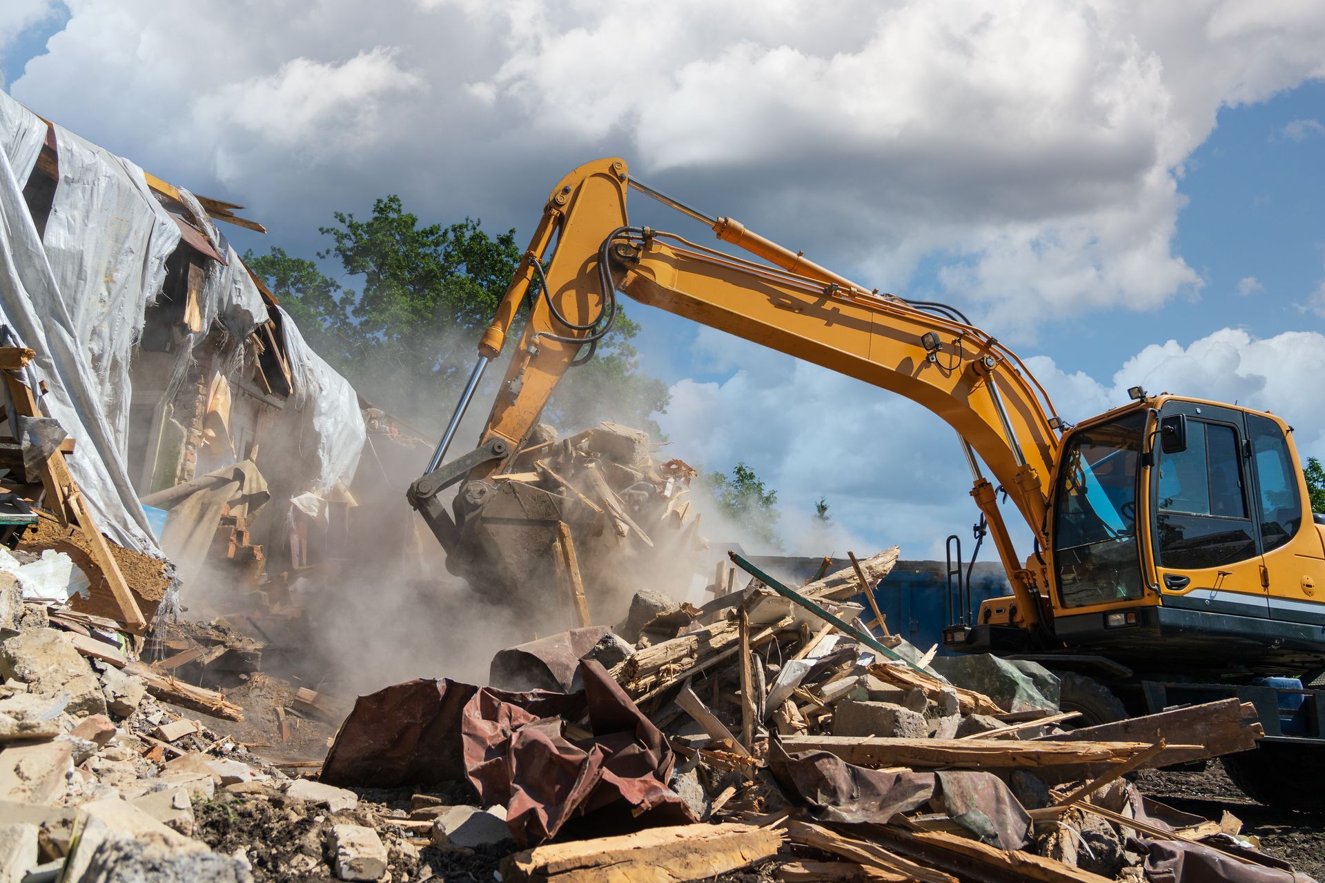 Yellow excavator demolishing a pile of rubble and debris under a cloudy sky Yellow excavator demolishing a pile of rubble and debris under a cloudy sky