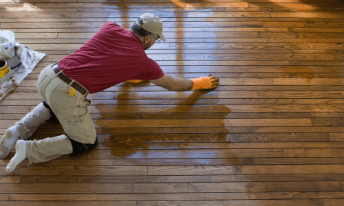 Sanded wood floor being stained. 