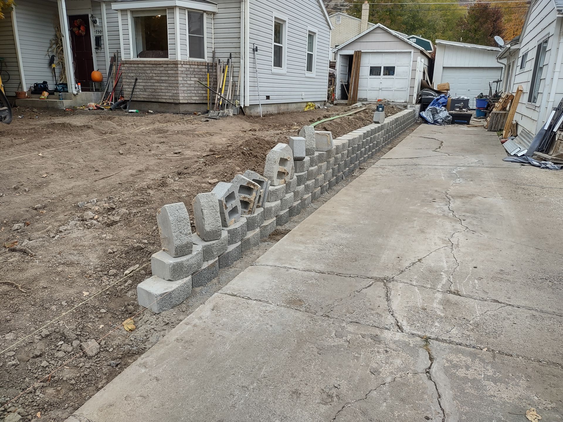 A construction worker is spreading concrete with a shovel.