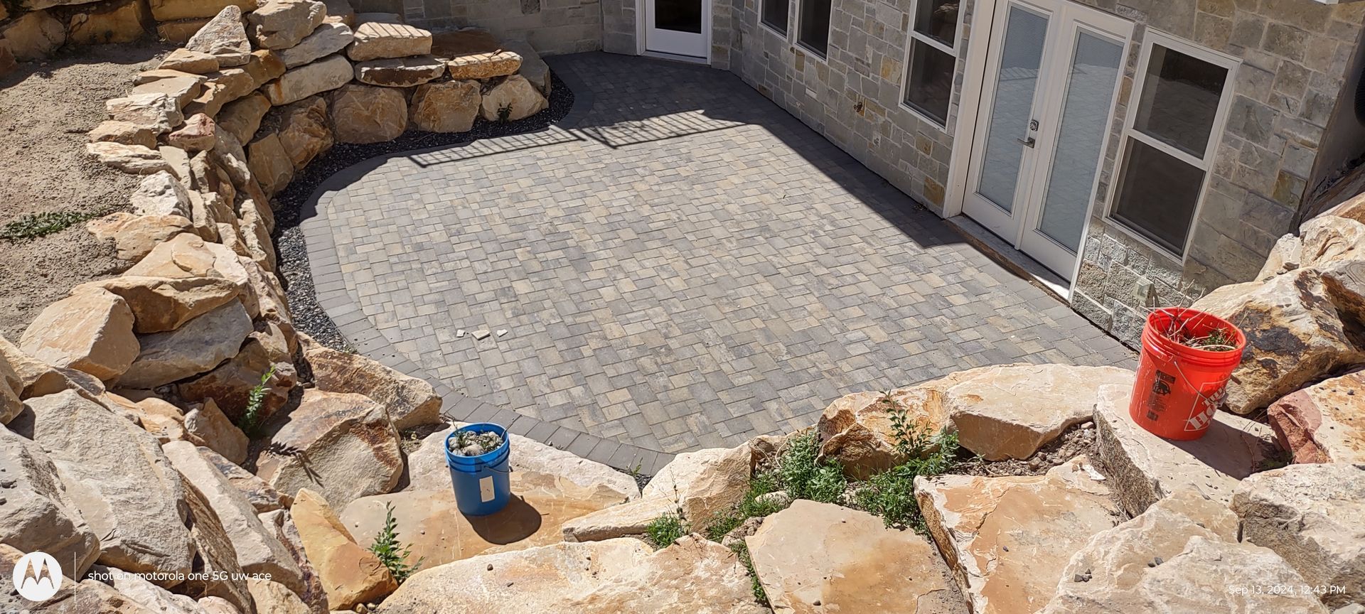 A man wearing gloves is laying bricks on a stone wall.