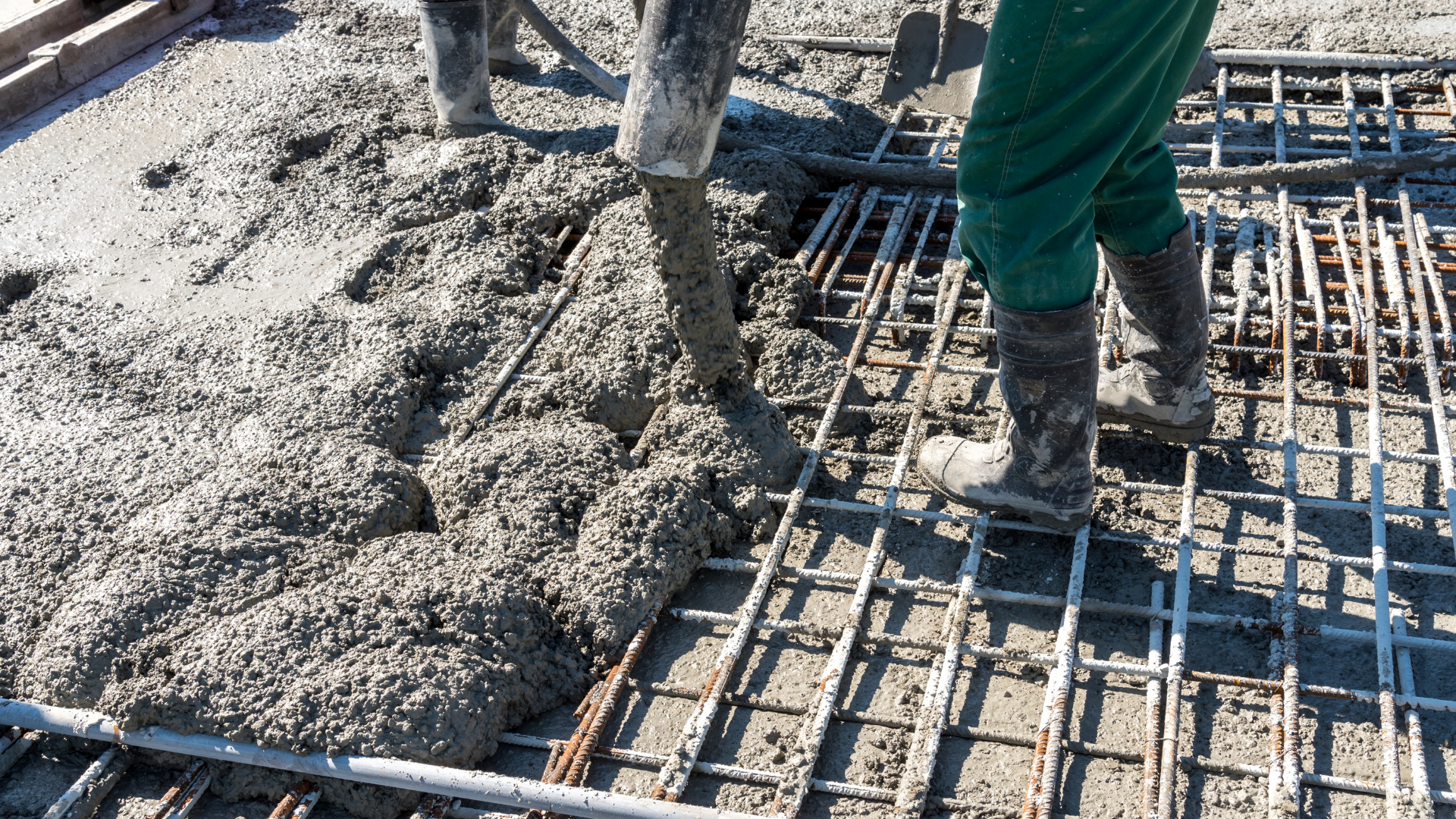 A person is pouring concrete into a grid on a construction site.