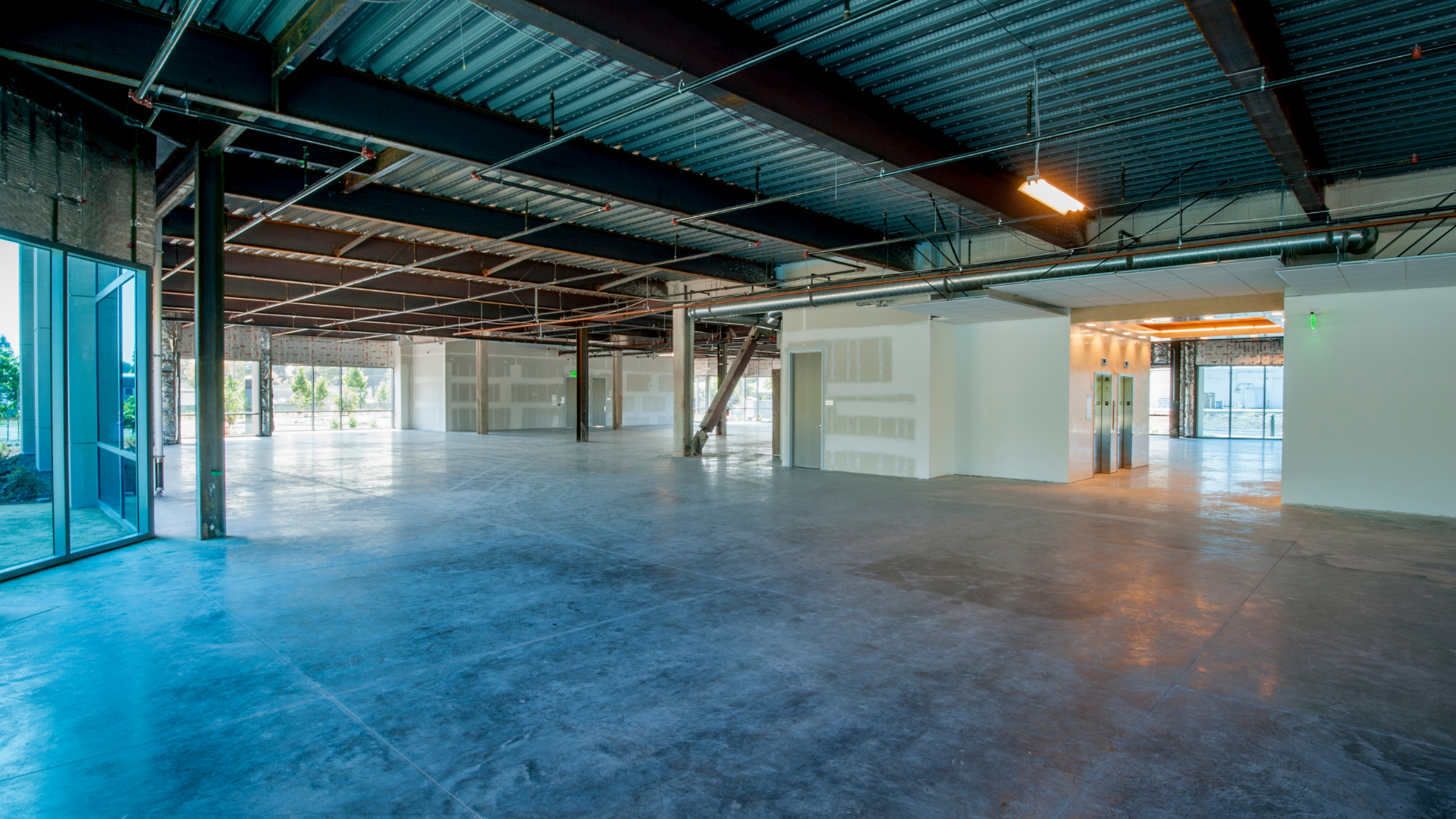 A large empty room with a concrete floor and a metal ceiling.