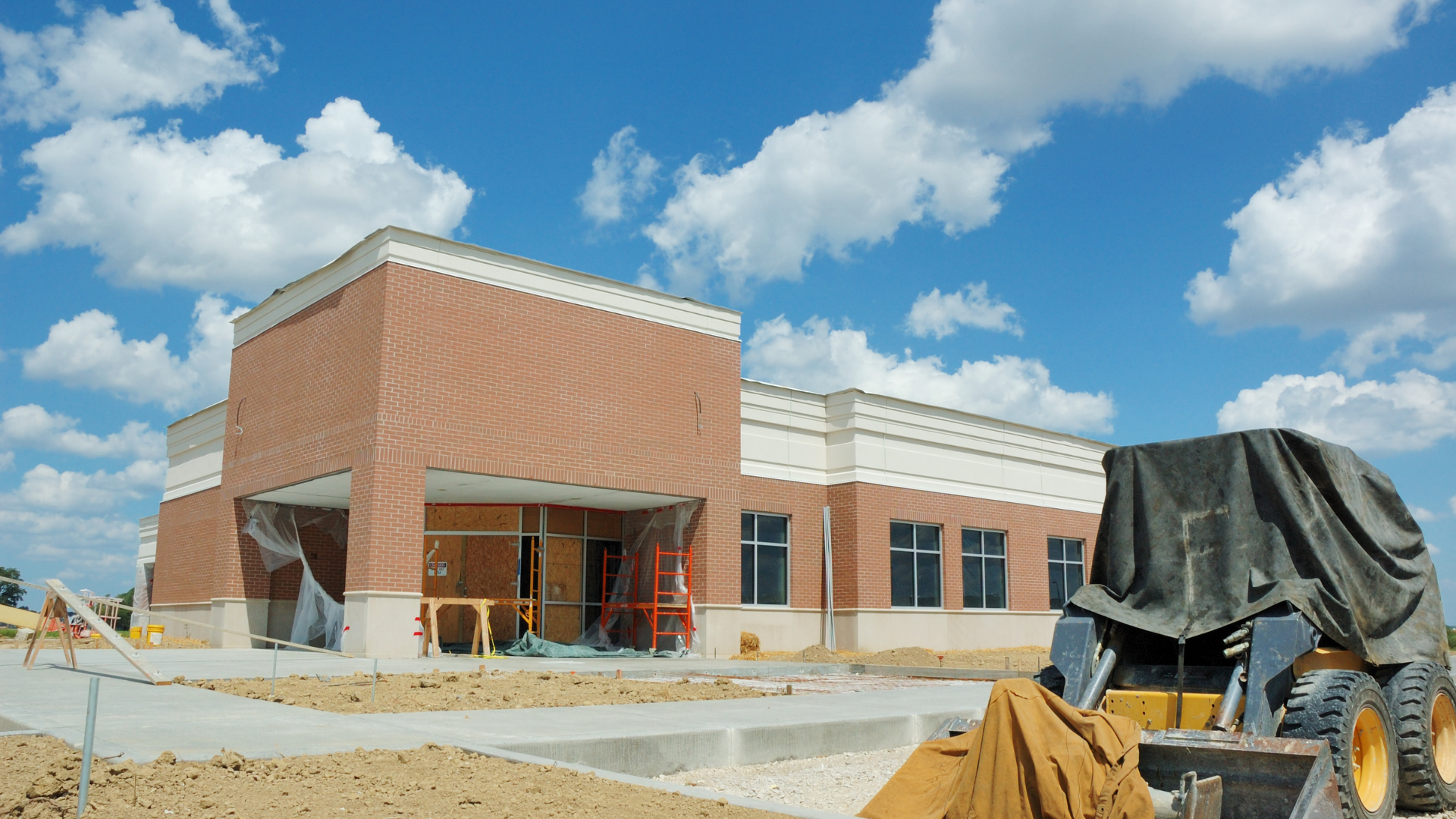 A large brick building under construction with a bulldozer in front of it