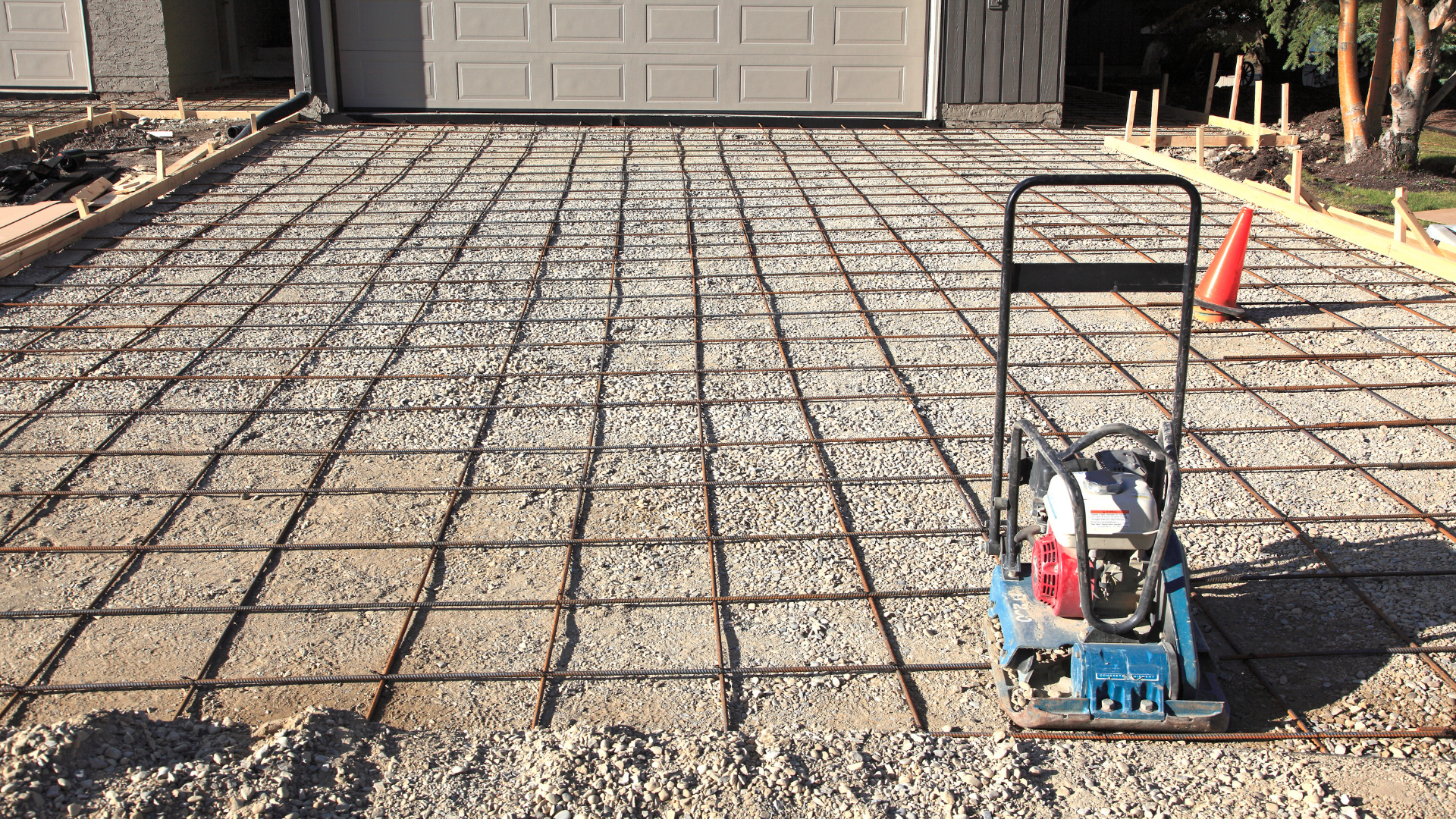 A compactor is sitting on top of a concrete driveway.