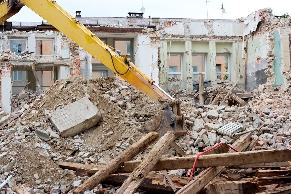 A yellow excavator is demolishing a building.
