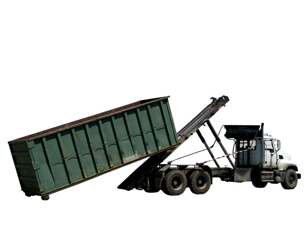 A dump truck is loading a green dumpster into it.