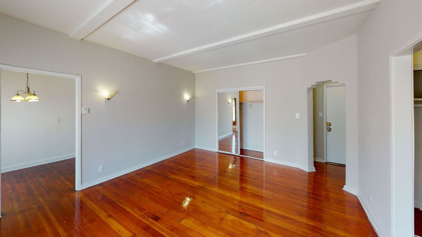 Empty room with wooden floors, gray walls, and multiple doorways.