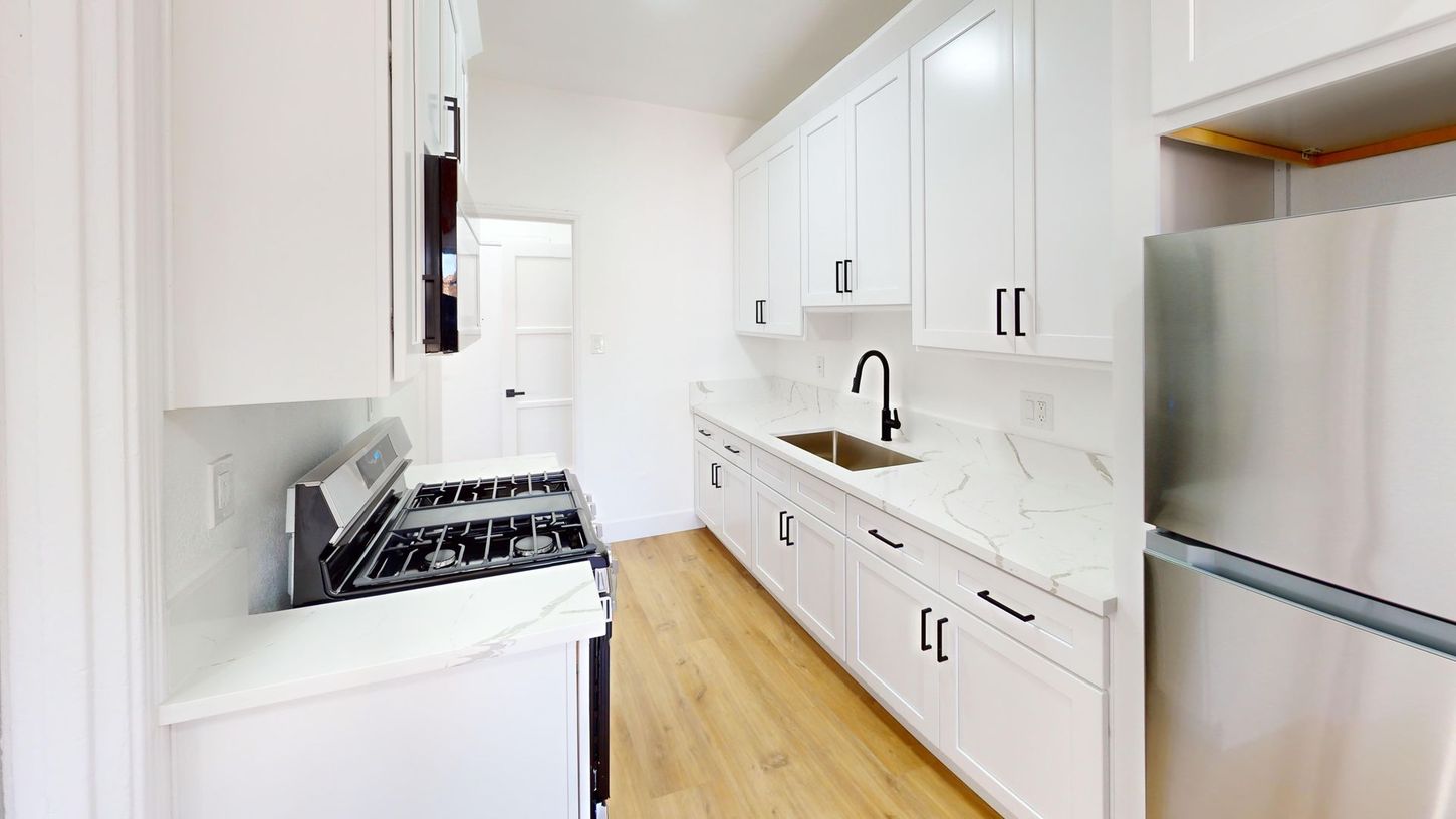 Bright, modern kitchen with white cabinets, light countertops, and stainless steel appliances.
