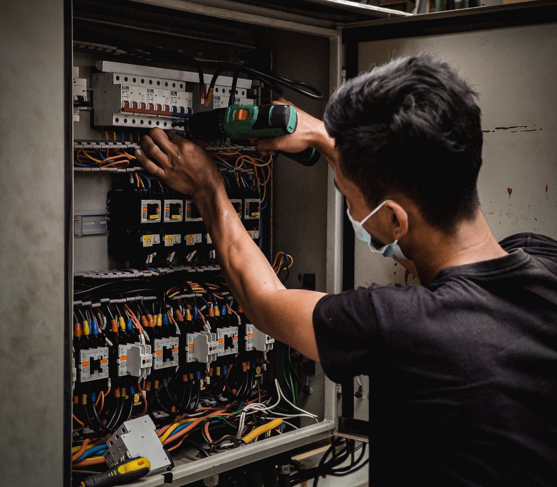 Man carefully repairing a breaker box with focused concentration.