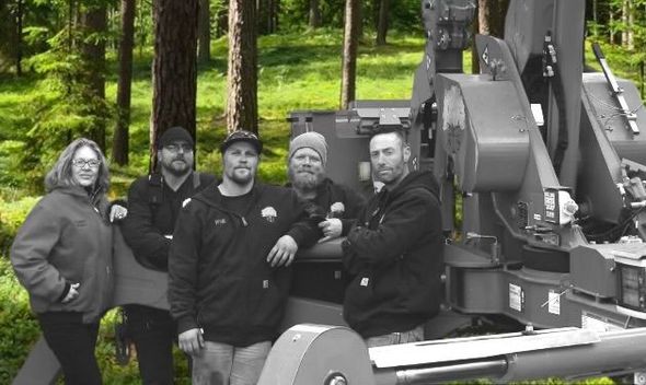 A group of people standing next to a machine in a forest.