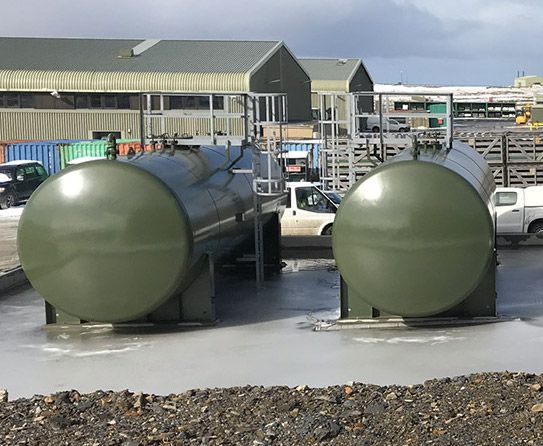 Two large green tanks are parked next to each other