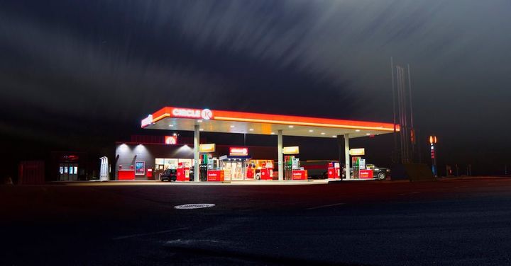 A gas station is lit up at night with a dark sky in the background.