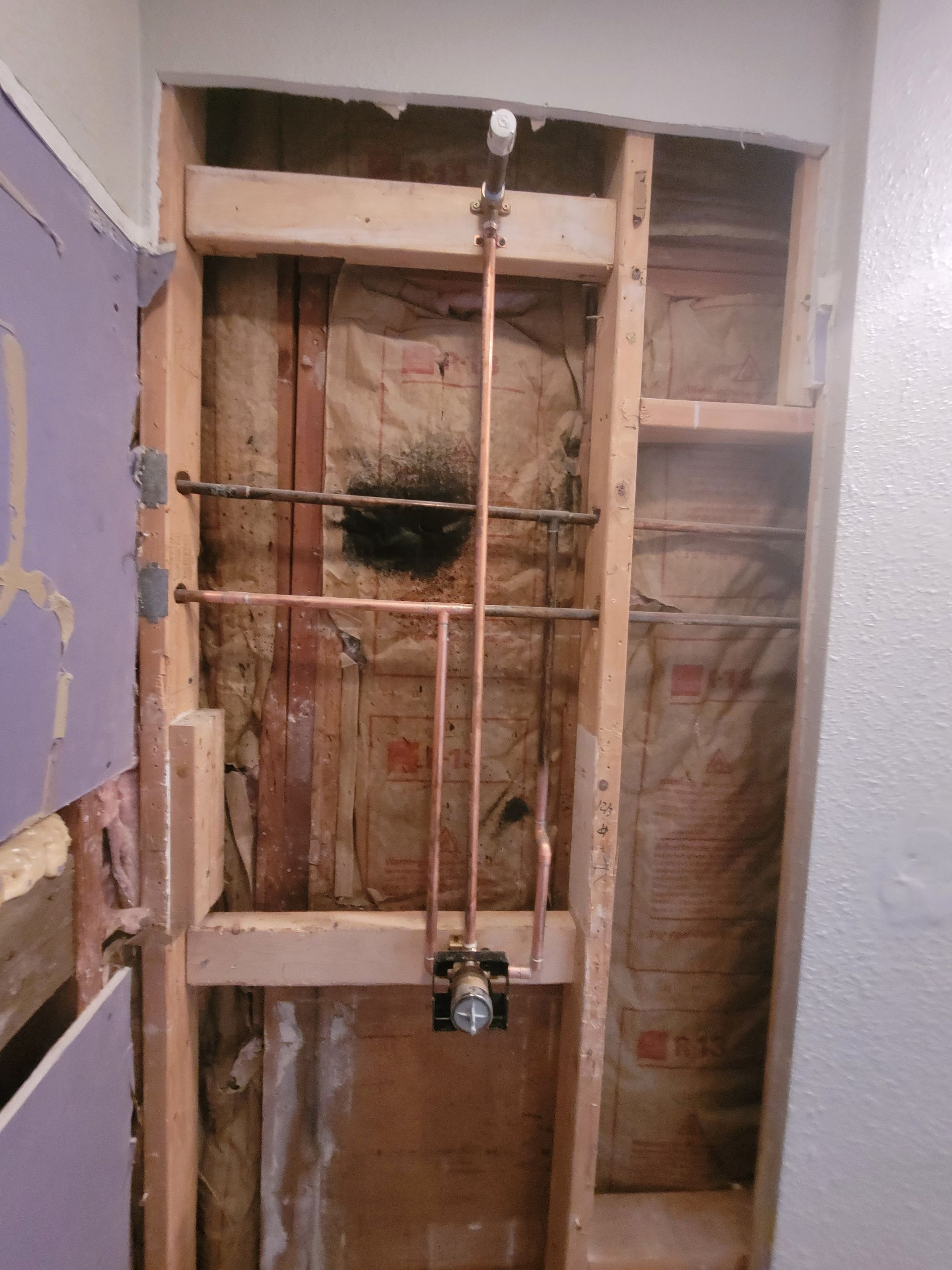 A bathroom under construction with a copper pipe coming out of the wall.