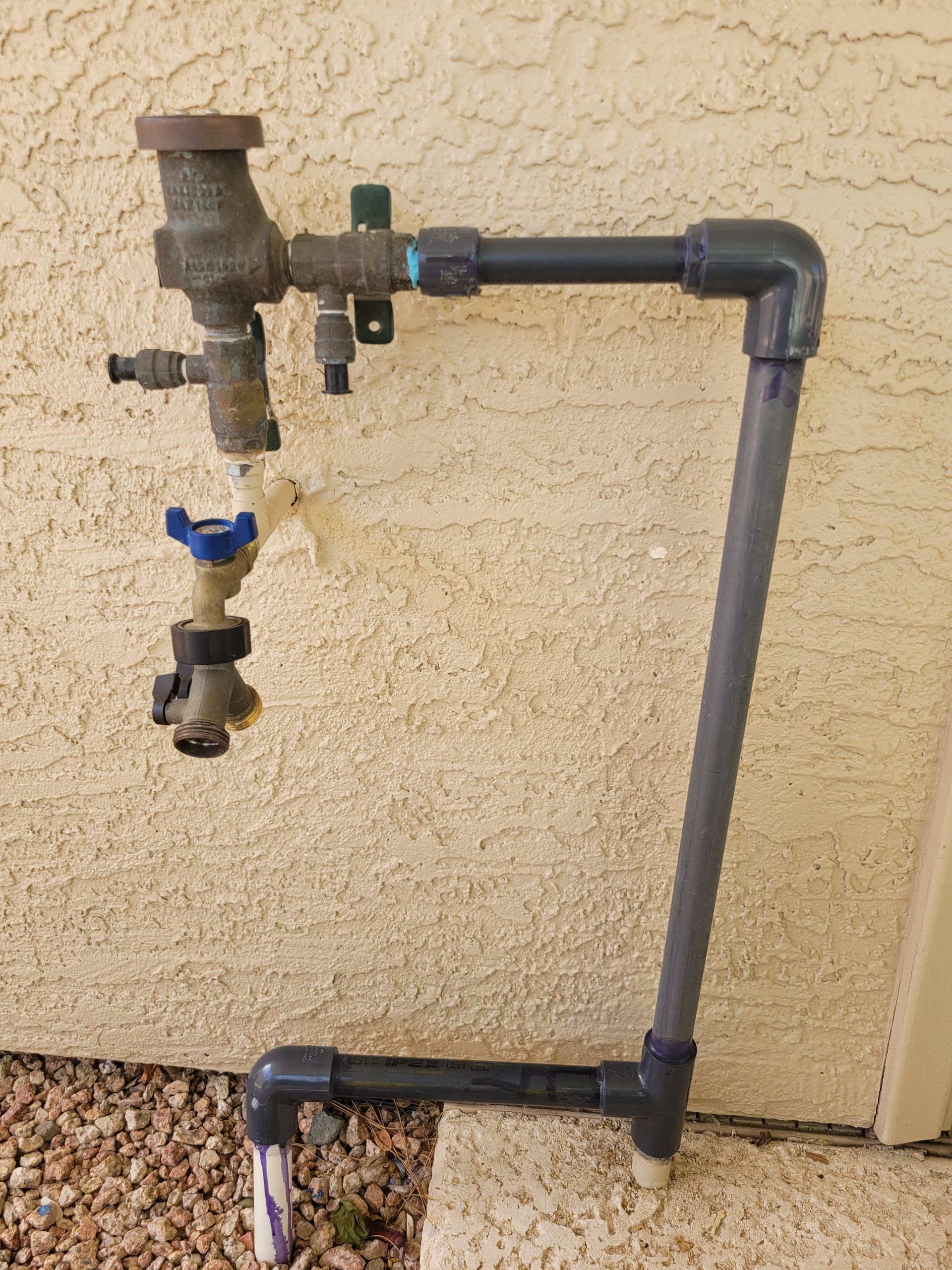 A faucet is attached to a wall with a pvc pipe.